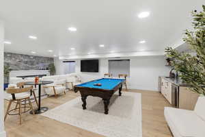 Game room featuring light wood-style flooring, bar with sink, billiards, beverage cooler, and recessed lighting