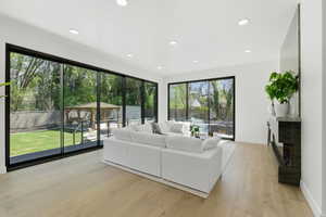 Living area with light wood finished floors, a fireplace, and recessed lighting