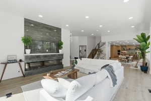 Living area featuring light wood-style floors, recessed lighting, and a high end fireplace
