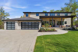 View of front of property with a front yard, concrete driveway, a garage, stone siding, and stucco siding