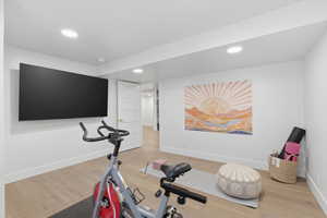 Workout room with light wood-style flooring and recessed lighting