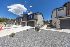 Modern townhome exteriors featuring wood-look siding accents, light-toned horizontal siding, and stone veneer bases