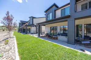 Rear exterior featuring multiple covered patios, a hot tub, and a manicured lawn