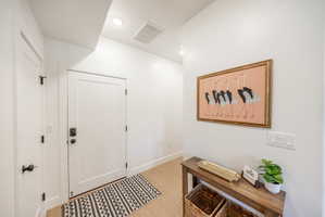 Entryway featuring light wood-finish flooring, recessed lighting, white trim, and a contemporary door with matte black hardware