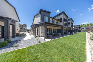 Contemporary multi-story residences featuring covered patios, private balconies, and an expansive grassy area