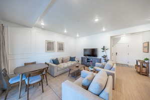 Bright living area featuring recessed lighting, wood-finish flooring, and white paneled accent walls