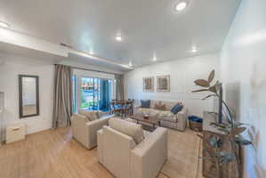 Open-concept living area featuring light wood-finish flooring, recessed lighting, and a sliding glass door providing natural light