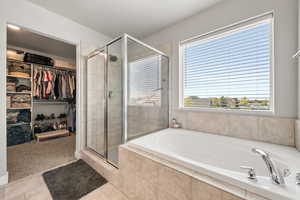 Full bathroom with a walk in closet, tile shower, and separate soaking tub