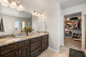 Full bath with a walk in closet, tiled flooring, and double vanity with extra storage