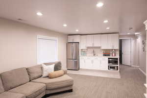 Living area with recessed lighting, light carpet, and light tile patterned floors