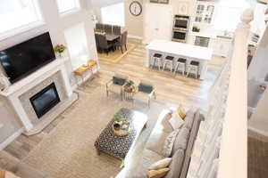 Living area with light wood-style floors, a premium fireplace, and a high ceiling