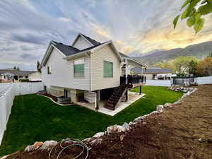 View of home's exterior featuring a deck with mountain view, a gate, a fenced backyard, a patio area, and roof with shingles