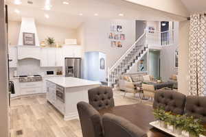 Kitchen featuring arched walkways, a center island, open floor plan, white cabinets, and light wood-style flooring