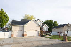 Traditional-style house with a garage, concrete driveway, stucco siding, brick siding, and roof with shingles