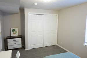 Bedroom featuring a textured ceiling, a closet, and dark carpet