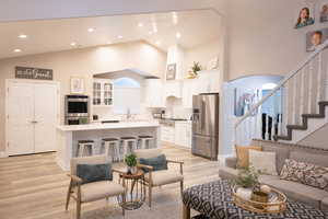 Living area with light wood finished floors, vaulted ceiling, arched walkways, and recessed lighting