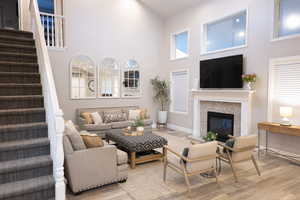 Living area with a high ceiling, wood finished floors, and a glass covered fireplace