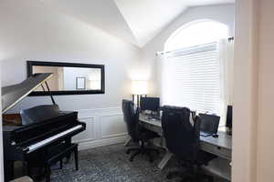 Office space with vaulted ceiling, a decorative wall, and a wainscoted wall