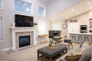 Living area featuring light wood-type flooring, recessed lighting, a tiled fireplace, and vaulted ceiling