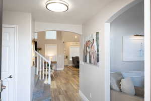 Hallway featuring arched walkways and light wood-style floors