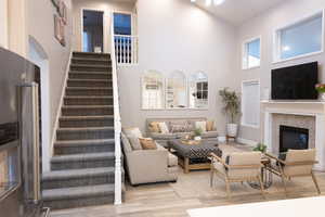 Living room featuring a high ceiling, a glass covered fireplace, and wood finished floors