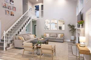 Living area with light wood-style flooring, ceiling fan, a high ceiling, and a fireplace