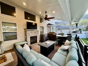 View of patio with outdoor lounge area, a wooden deck, a ceiling fan, and a fireplace