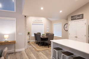 Kitchen with a kitchen bar, light wood-type flooring, lofted ceiling, recessed lighting, and light countertops