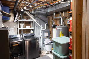 Storage room featuring independent washer and dryer, water heater, and heating unit