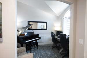 Office area featuring lofted ceiling, a decorative wall, and wainscoting