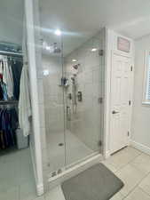 Bathroom with light tile patterned flooring, a stall shower, a spacious closet, and a textured ceiling