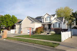 Traditional-style house with driveway, stucco siding, a garage, and a shingled roof