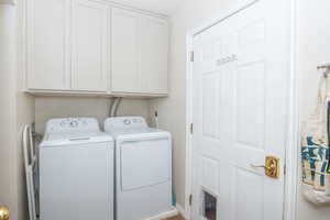 Laundry room featuring washer and dryer, cabinet space. This door leads into the garage. Not shown is additional pantry space and a small gun safe built into the wall.