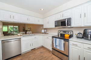 Kitchen featuring stainless steel appliances, white cabinetry,  recessed lighting, and quartz counters.