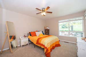 East bedroom with new carpet, big windows, and a ceiling fan.