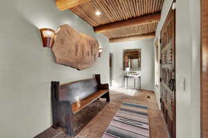 Hall with a wooden ceiling with exposed beams and recessed lighting