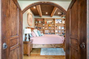 Bedroom with light wood-style floors, a wood ceiling with exposed beams, and recessed lighting