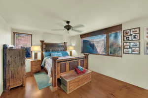 Bedroom featuring wood finished floors, multiple windows, and ceiling fan