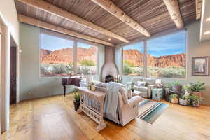 Living room featuring a mountain view, light wood-type flooring, beamed ceiling, a fireplace, and healthy amount of natural light