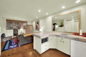 Kitchen featuring dishwasher, arched walkways, stainless steel microwave, recessed lighting, and dark wood-style flooring