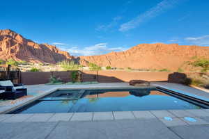 Integrated pool / spa with a mountain view, a fenced backyard, and a patio area