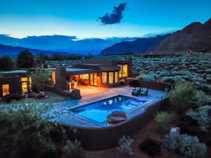 Back of house featuring a patio area, a mountain view, and an in-ground hot tub