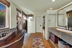 Full bathroom featuring vanity, a freestanding bath, walk in shower, light wood finished floors, and recessed lighting