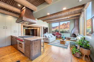 Two tone kitchen featuring open floor plan, designer range, island range hood, light wood-style floors, and a mountain view