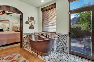Ensuite bathroom featuring a wainscoted wall, ceiling fan, light wood finished floors, a freestanding tub, and recessed lighting