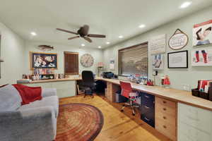 Home office with built in study area, light wood finished floors, recessed lighting, and a ceiling fan