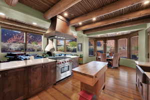 Kitchen featuring island exhaust hood, premium stove, light wood finished floors, wooden counters, and a wood ceiling with exposed beams