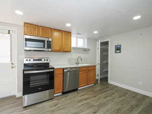 Lower Level - Kitchen featuring stainless steel appliances, light countertops, wood finish cabinetry, a textured ceiling, and recessed lighting