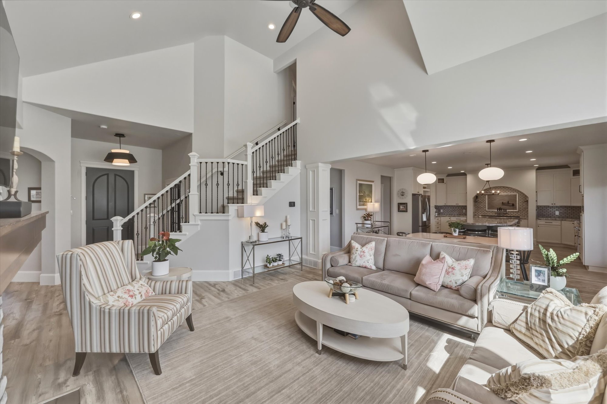 Living area featuring recessed lighting, light wood-style flooring, a ceiling fan, arched walkways, and vaulted ceiling