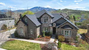 View of front facade with stone siding, a mountain view, a front yard, and brick siding